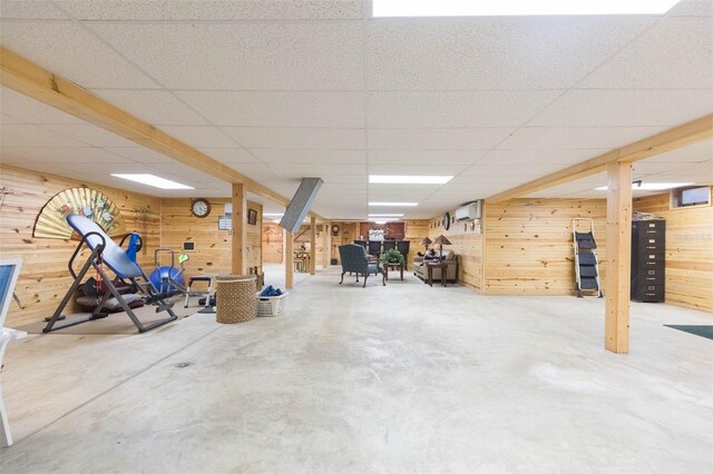 finished basement featuring wood walls and a drop ceiling