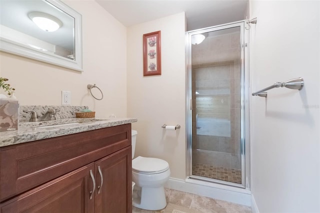 bathroom with toilet, baseboards, a shower stall, and vanity