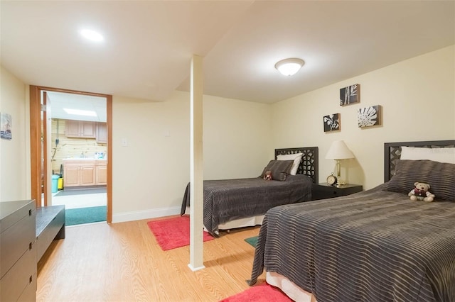 bedroom featuring a sink, baseboards, and light wood finished floors
