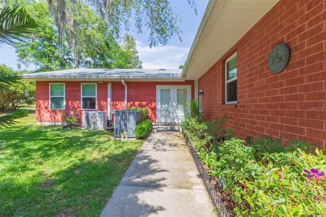 view of exterior entry with a lawn and brick siding