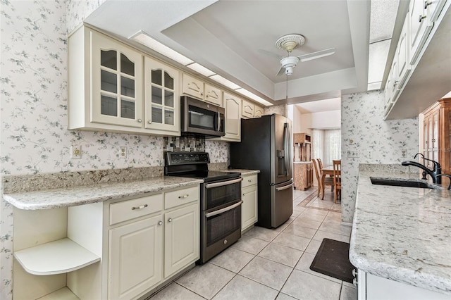 kitchen with stainless steel appliances, open shelves, wallpapered walls, and a sink