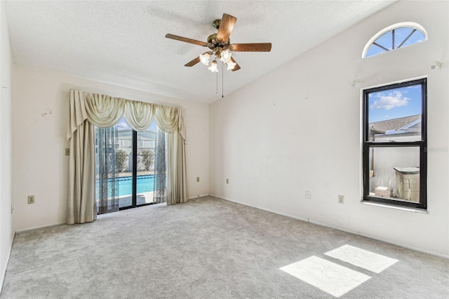 carpeted spare room with lofted ceiling, a textured ceiling, and ceiling fan