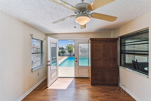 doorway featuring a textured ceiling, a ceiling fan, dark wood-style floors, and baseboards
