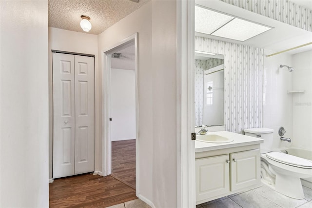 bathroom with vanity, shower / bath combination, toilet, wallpapered walls, and wood finished floors