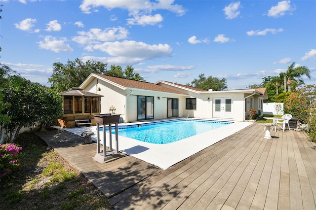 pool featuring french doors, a wooden deck, and a sunroom