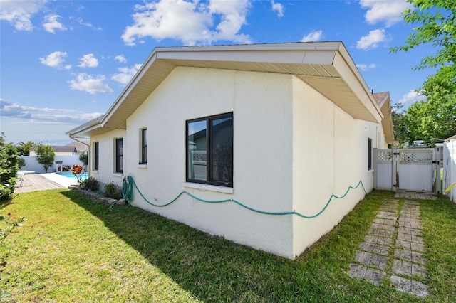 view of home's exterior featuring stucco siding, fence, a gate, and a yard