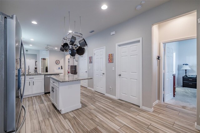 4516 Savannah Holly Pl, Riverview, FL 33578 - kitchen with white cabinetry, wood finish floors, appliances with stainless steel finishes, light stone countertops, and a kitchen island