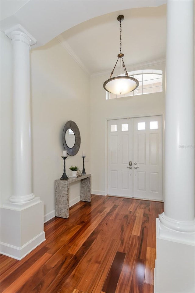 foyer featuring decorative columns, wood finished floors, and crown molding