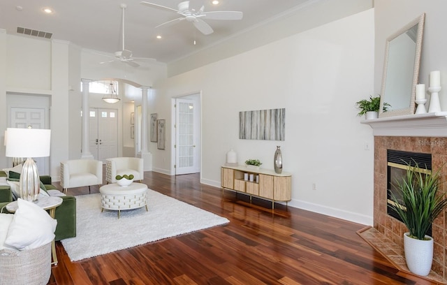 living room featuring decorative columns, crown molding, a ceiling fan, visible vents, and wood finished floors