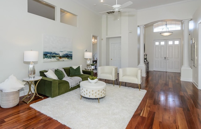 living area with ornamental molding, dark wood-style floors, a towering ceiling, and ornate columns