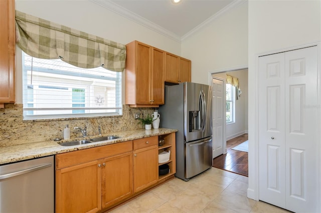 kitchen with stainless steel appliances, decorative backsplash, crown molding, and a sink