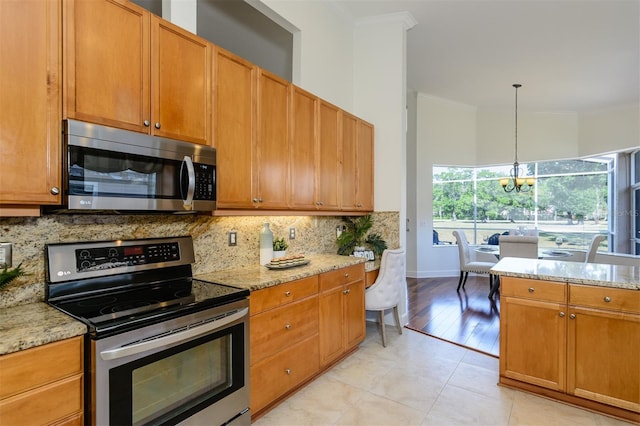 kitchen featuring appliances with stainless steel finishes, light stone counters, decorative backsplash, and ornamental molding