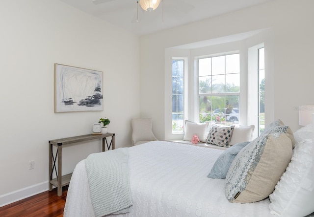 bedroom with a ceiling fan, baseboards, dark wood finished floors, and multiple windows