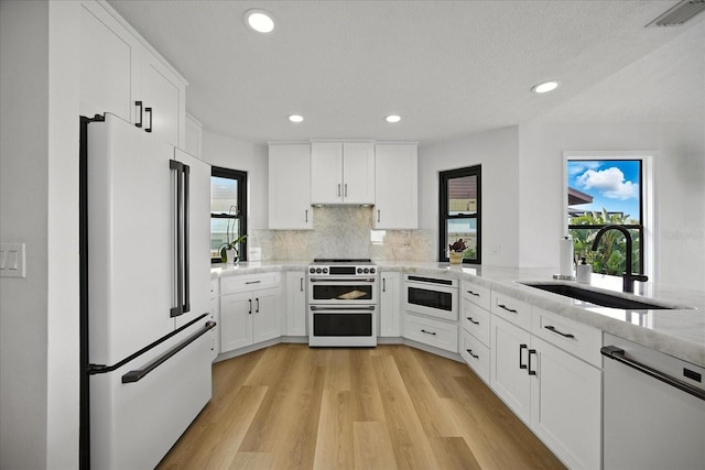 6627 Dolphin Cove Dr, Apollo Beach, FL 33572 - kitchen with premium appliances, recessed lighting, light wood-type flooring, white cabinetry, and tasteful backsplash