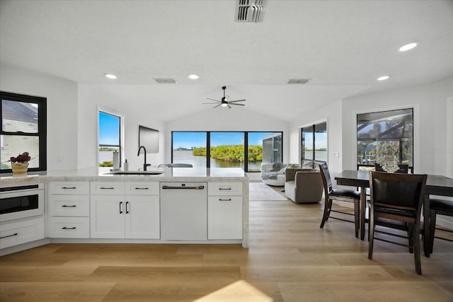 6627 Dolphin Cove Dr, Apollo Beach, FL 33572 - kitchen with white appliances, white cabinets, light wood-style flooring, a ceiling fan, and lofted ceiling
