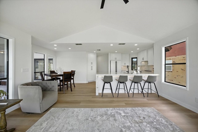 6627 Dolphin Cove Dr, Apollo Beach, FL 33572 - kitchen with a kitchen breakfast bar, a peninsula, white cabinetry, light wood-style floors, and lofted ceiling