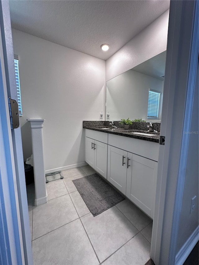 6942 Ripple Pond Loop, Zephyrhills, FL 33541 - bathroom with double vanity, a sink, a textured ceiling, and tile patterned flooring