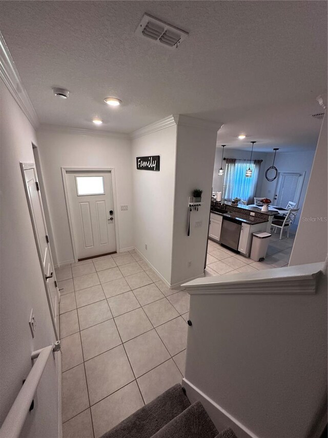 6942 Ripple Pond Loop, Zephyrhills, FL 33541 - foyer entrance with crown molding, a textured ceiling, baseboards, light tile patterned floors, and visible vents