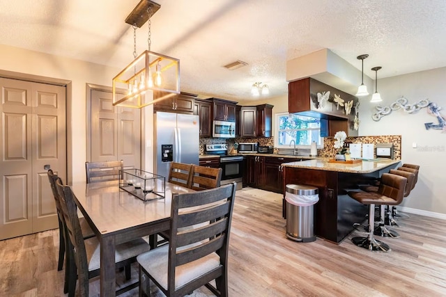 2460 Beacon Groves Blvd, Palm Harbor, FL 34683 - dining room with light wood-style floors, baseboards, a textured ceiling, and visible vents