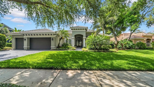mediterranean / spanish home with decorative driveway, a garage, stucco siding, and a tiled roof