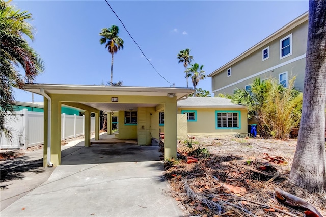 view of front of property with fence, driveway, an attached carport, and stucco siding