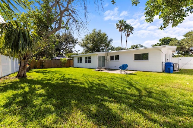 back of property featuring a lawn, central AC unit, and a fenced backyard