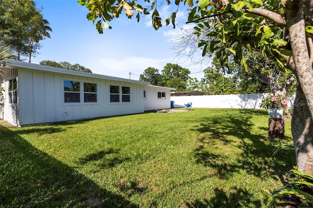 rear view of property with fence, board and batten siding, and a lawn