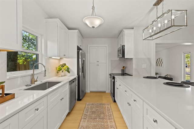 kitchen with a sink, white cabinets, appliances with stainless steel finishes, and a healthy amount of sunlight