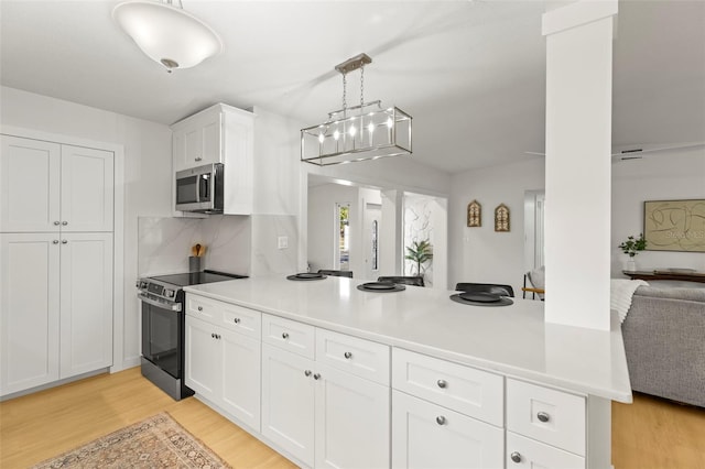 kitchen with white cabinets, light wood-style floors, stainless steel appliances, open floor plan, and a peninsula