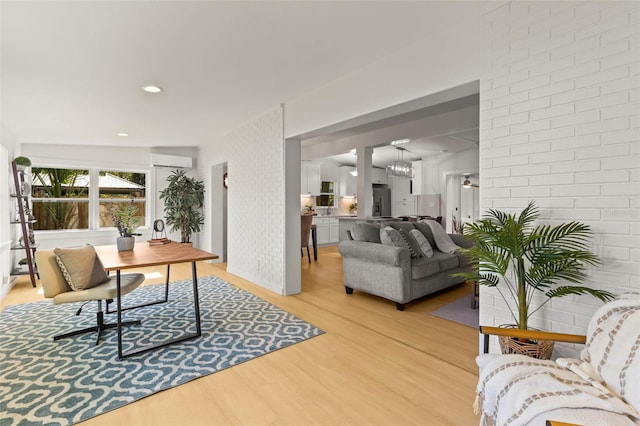 home office with a wall unit AC, light wood finished floors, and a notable chandelier