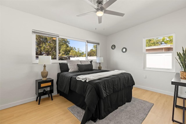 bedroom featuring baseboards, light wood finished floors, and multiple windows