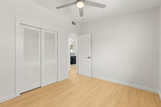 unfurnished bedroom featuring a closet, a ceiling fan, visible vents, light wood-style flooring, and baseboards