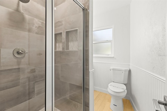 bathroom featuring a stall shower, toilet, and wood finished floors
