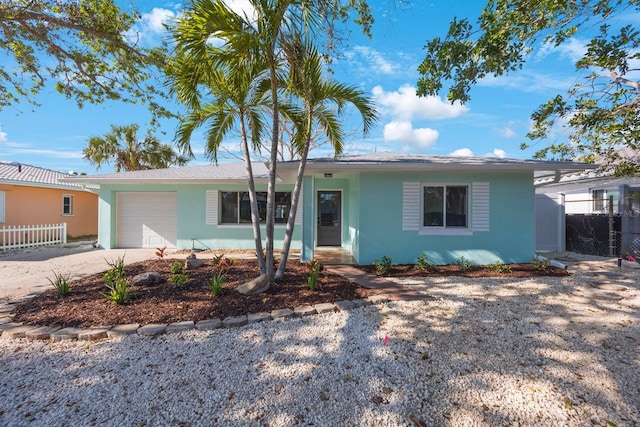 ranch-style home with a garage, stucco siding, driveway, and fence
