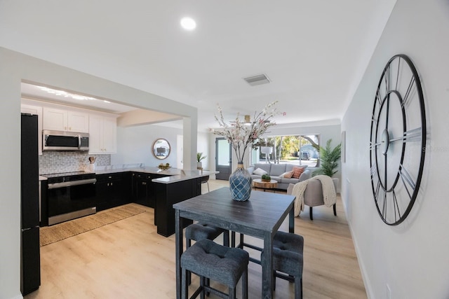dining room featuring baseboards, light wood-style floors, and visible vents