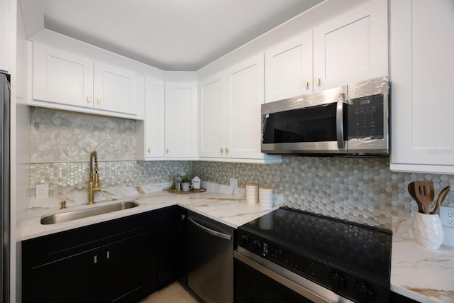 kitchen featuring white cabinets, dark cabinetry, stainless steel appliances, and a sink