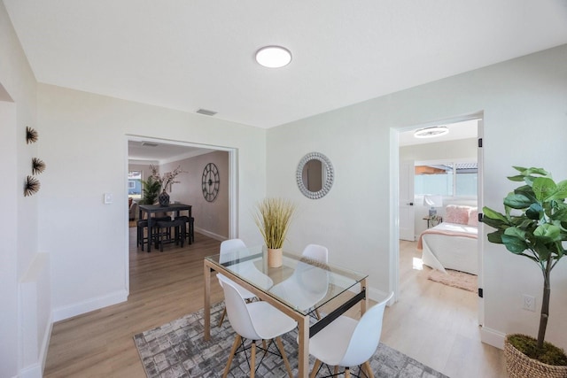 dining room with light wood finished floors, baseboards, and visible vents