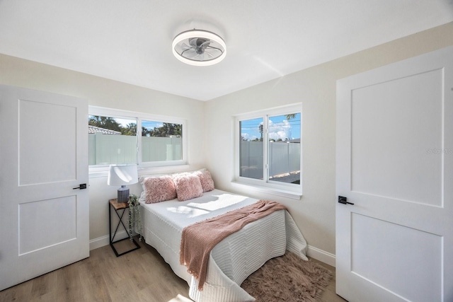bedroom featuring light wood-style flooring, baseboards, and multiple windows