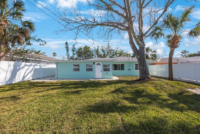 back of house featuring a fenced backyard, a yard, and stucco siding