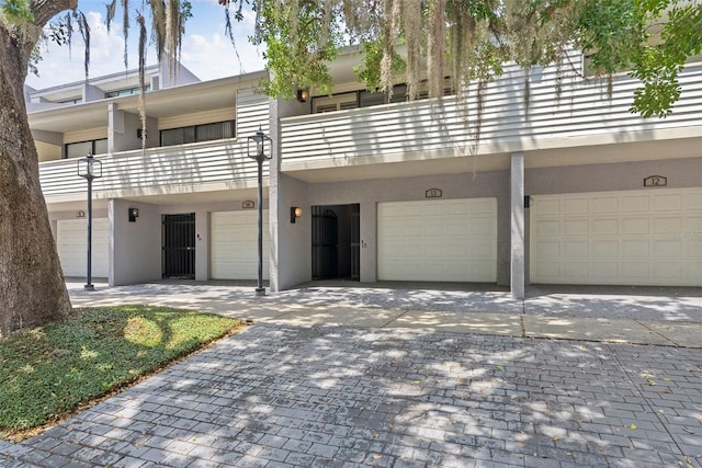 townhome / multi-family property with driveway, a garage, and stucco siding