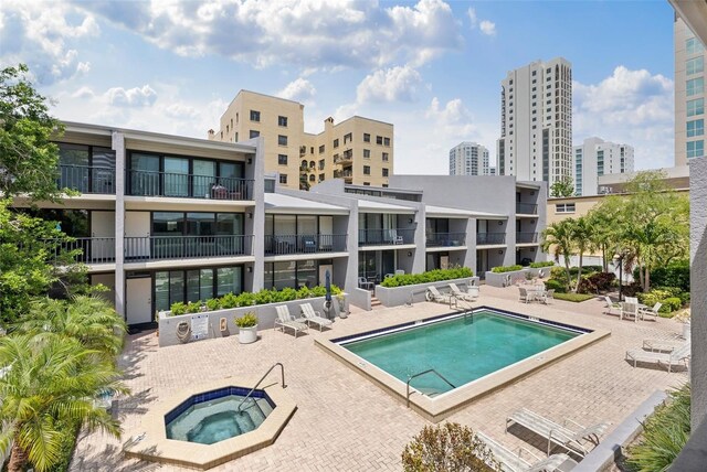 community pool with a view of city, a patio area, and a community hot tub