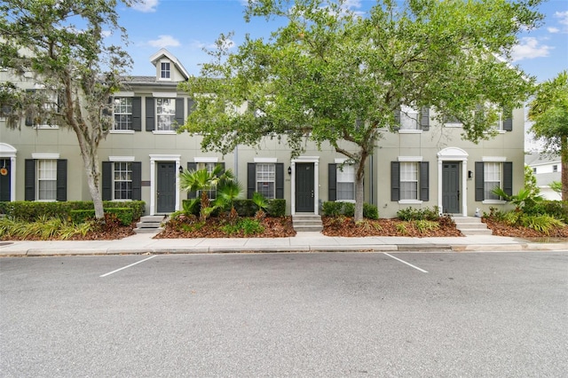 multi unit property with entry steps, stucco siding, and uncovered parking