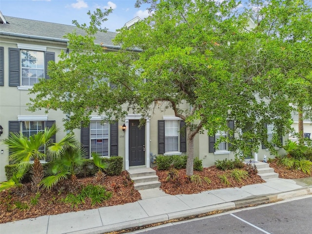 view of property with uncovered parking and stucco siding