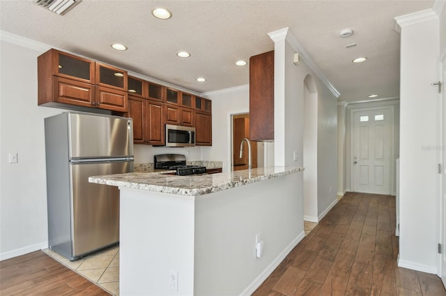 kitchen with crown molding, light stone countertops, light wood-style floors, recessed lighting, and appliances with stainless steel finishes