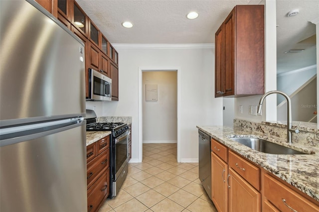 kitchen featuring crown molding, a sink, light tile patterned floors, light stone counters, and stainless steel appliances