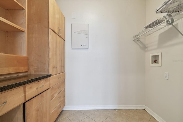 laundry area with baseboards, light tile patterned floors, laundry area, and washer hookup