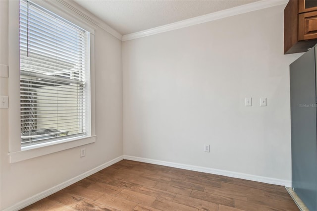 unfurnished room with baseboards, ornamental molding, wood finished floors, and a wealth of natural light