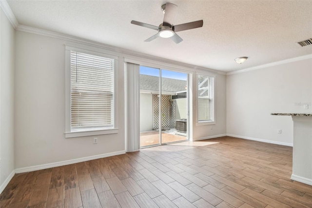 unfurnished room featuring ceiling fan, visible vents, wood finished floors, baseboards, and ornamental molding