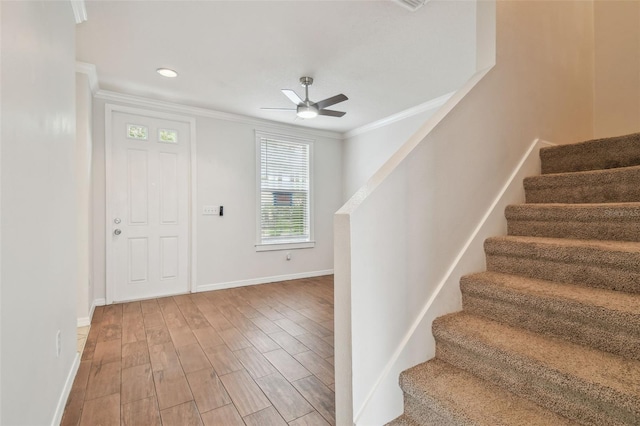 foyer with crown molding, stairs, wood finished floors, baseboards, and ceiling fan