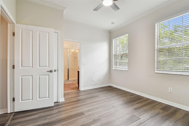 unfurnished bedroom featuring baseboards, ornamental molding, wood finished floors, and ensuite bath